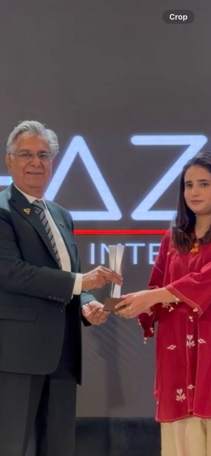 Mahnoor receiving an award on stage at IAPEX 26 for her natural building workshop