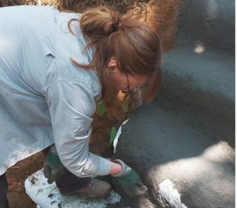 A participant shaping an earthen surface by hand with gloves in Nepal