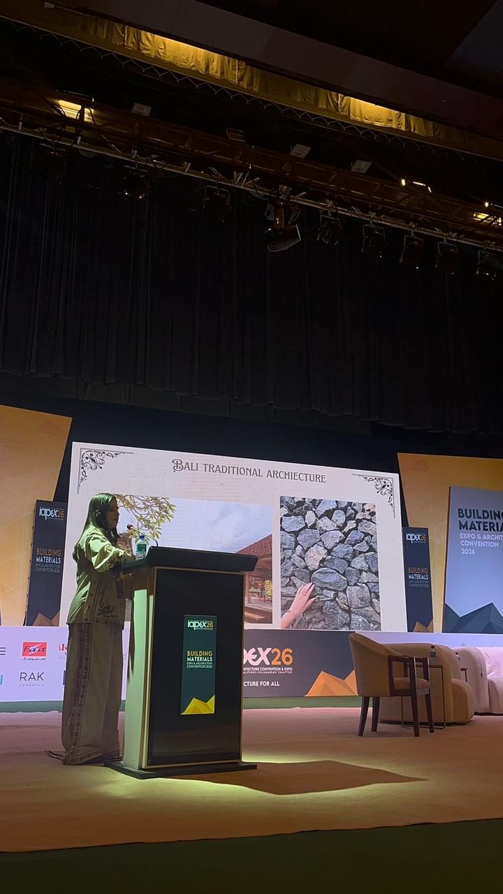 Mahnoor speaking at a podium in front of a slide on Bali traditional architecture